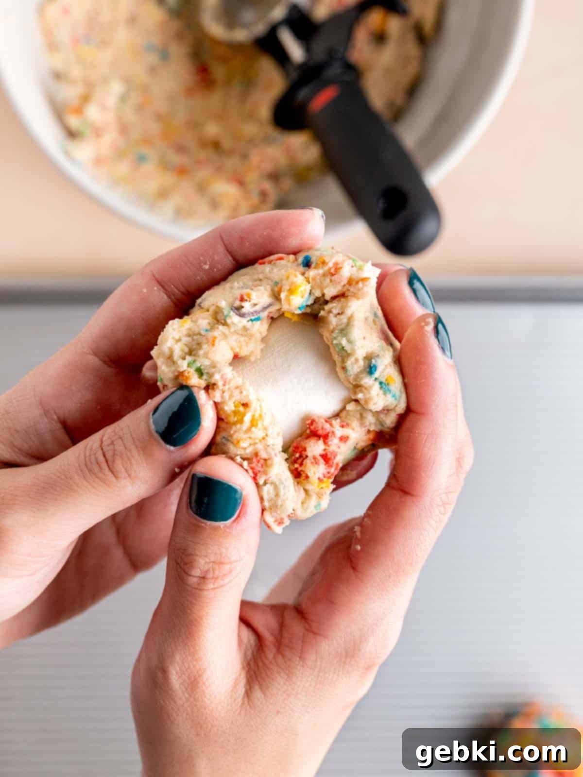 Wrapping Fruity Pebbles cookie dough around a marshmallow.