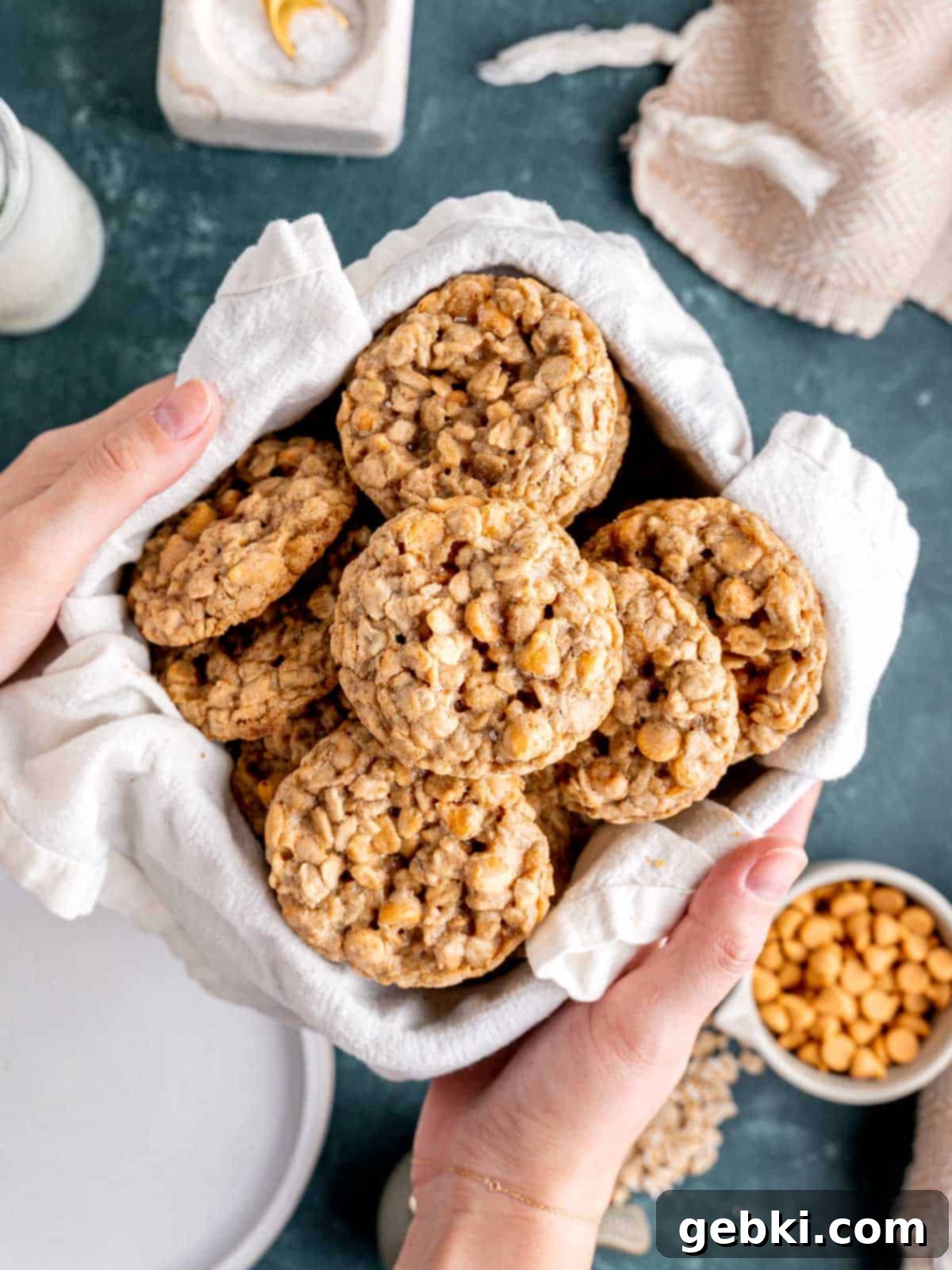Chewy Sea Salt Butterscotch Oat Cookies 2 Hands holding a rustic basket overflowing with golden-brown butterscotch oatmeal cookies, lightly sprinkled with flaky sea salt.