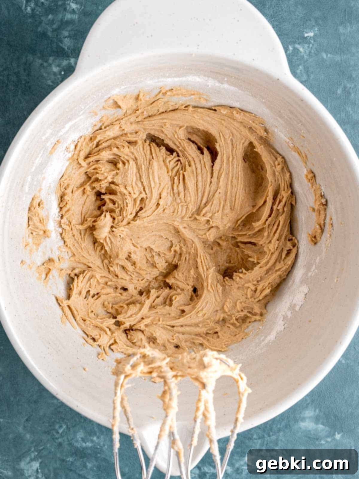 Chewy Sea Salt Butterscotch Oat Cookies 5 Dry ingredients, including all-purpose flour, baking soda, ground cinnamon, and salt, being gently stirred into the wet ingredients in a large mixing bowl.