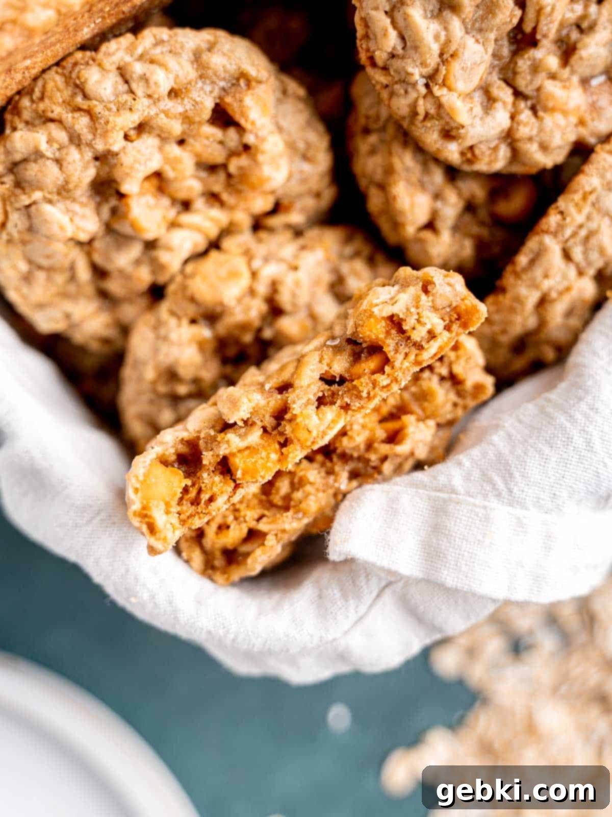 Chewy Sea Salt Butterscotch Oat Cookies 8 A warm butterscotch oatmeal cookie perfectly broken in half, showcasing its soft, chewy interior studded with melted butterscotch chips and flecks of oat.