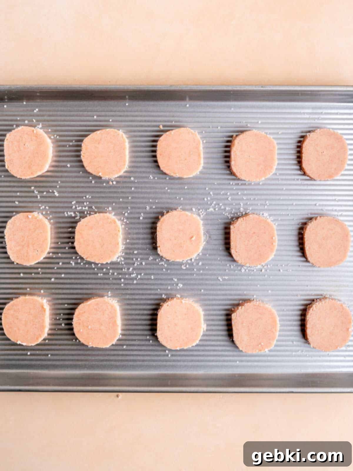 Effortless Strawberry Shortbread Cookies 8 Strawberry shortbread cookie slices neatly arranged on a parchment paper-lined baking sheet, ready for baking.
