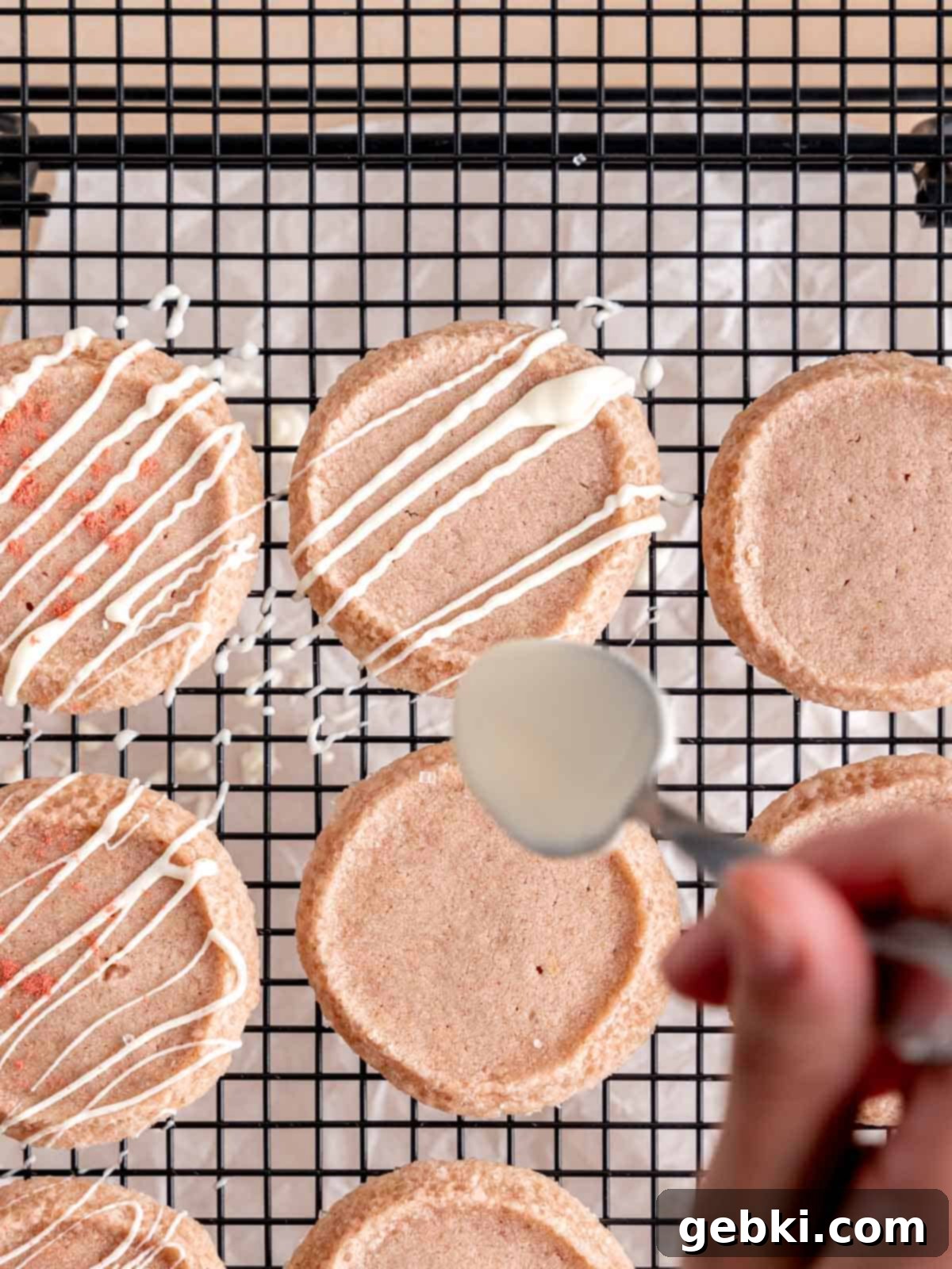 Effortless Strawberry Shortbread Cookies 9 Drizzling melted white chocolate over freshly baked strawberry shortbread cookies.