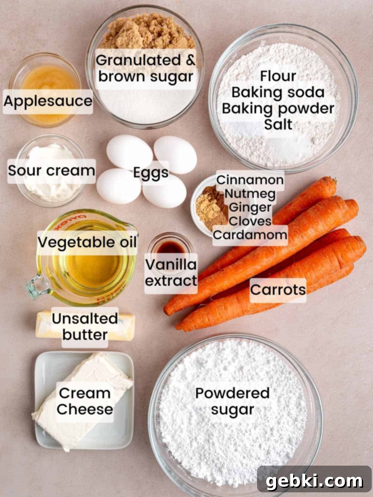 Assortment of fresh ingredients like carrots, spices, eggs, and cream cheese for making spiced carrot cake.