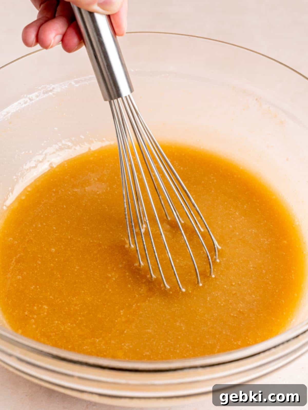 Mixing wet ingredients, including sugar, oil, eggs, and applesauce, for carrot cake batter.