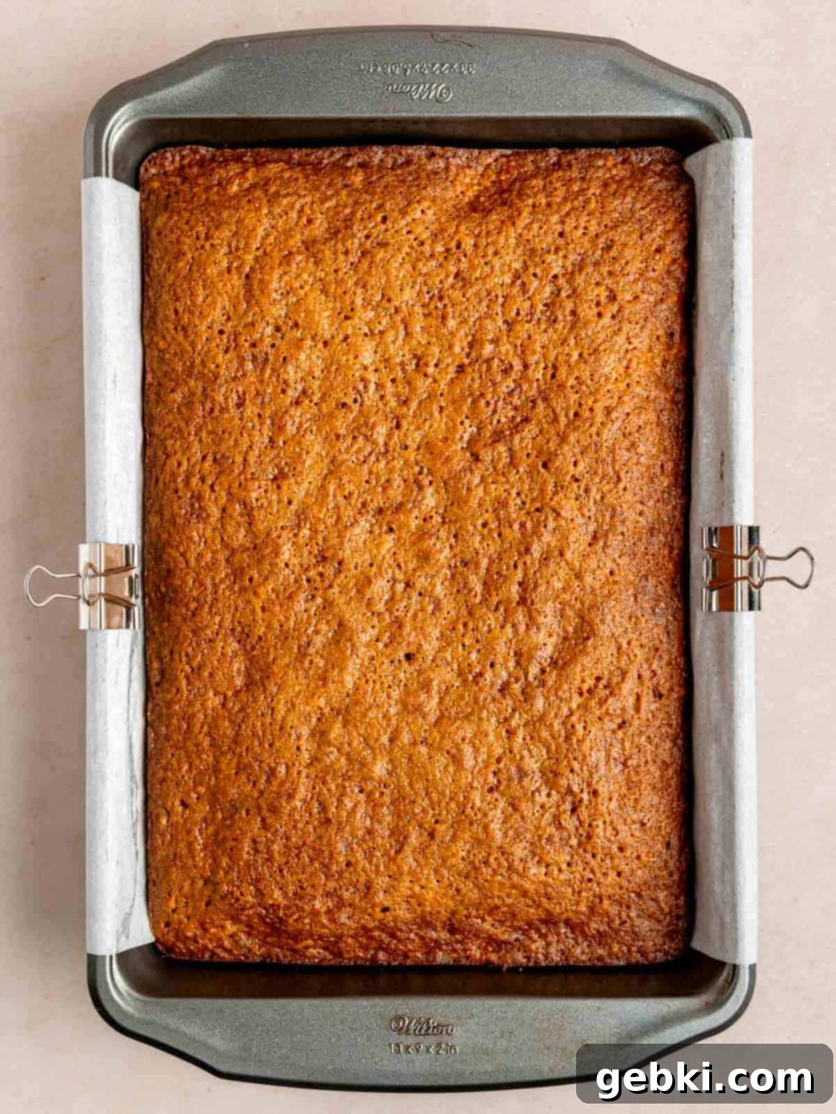 A beautifully baked spiced carrot cake in a 9x13 inch sheet pan, ready for frosting.
