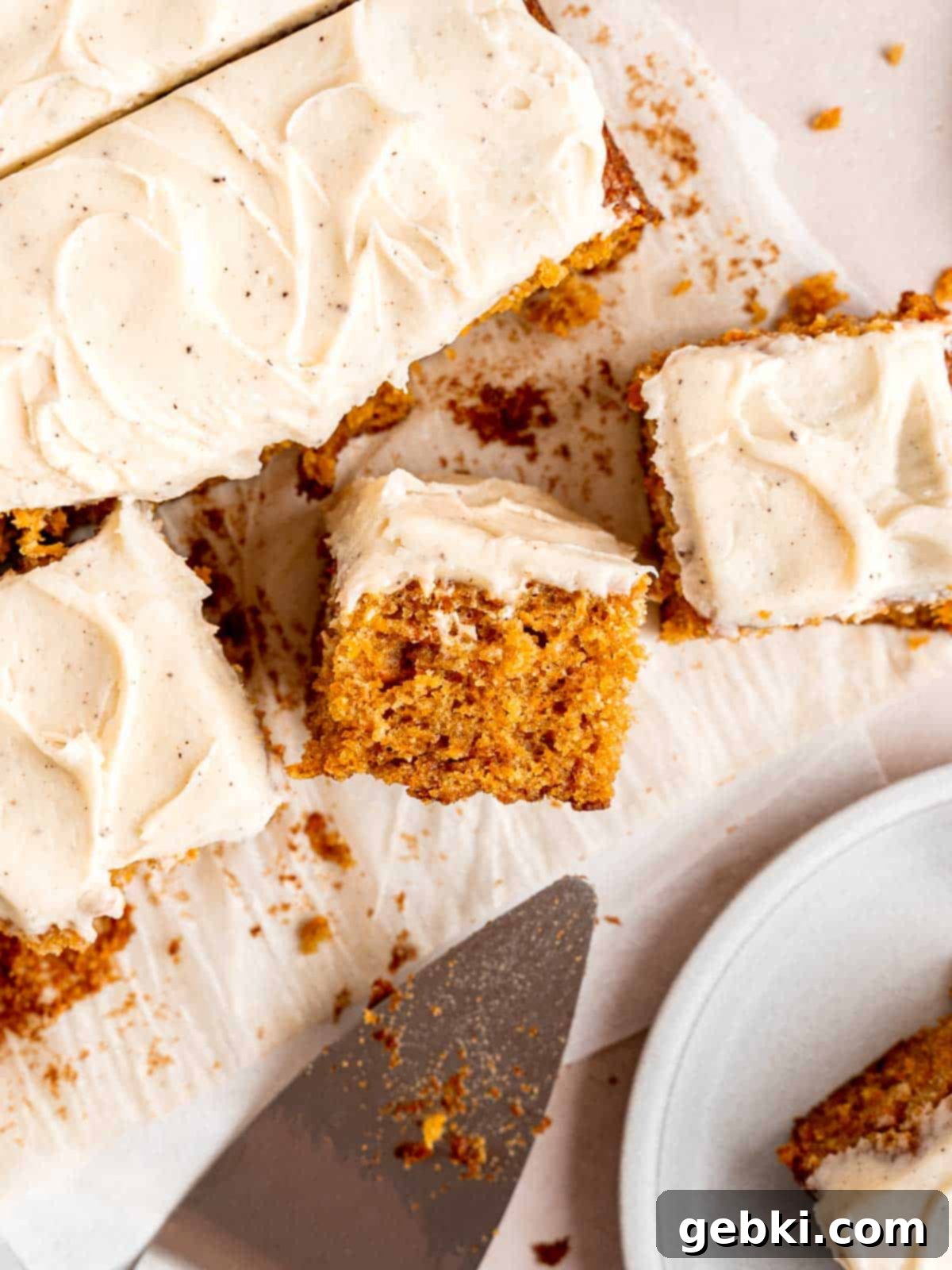 A top-down view of a freshly baked spiced carrot sheet cake with brown butter frosting, cut into perfect squares.