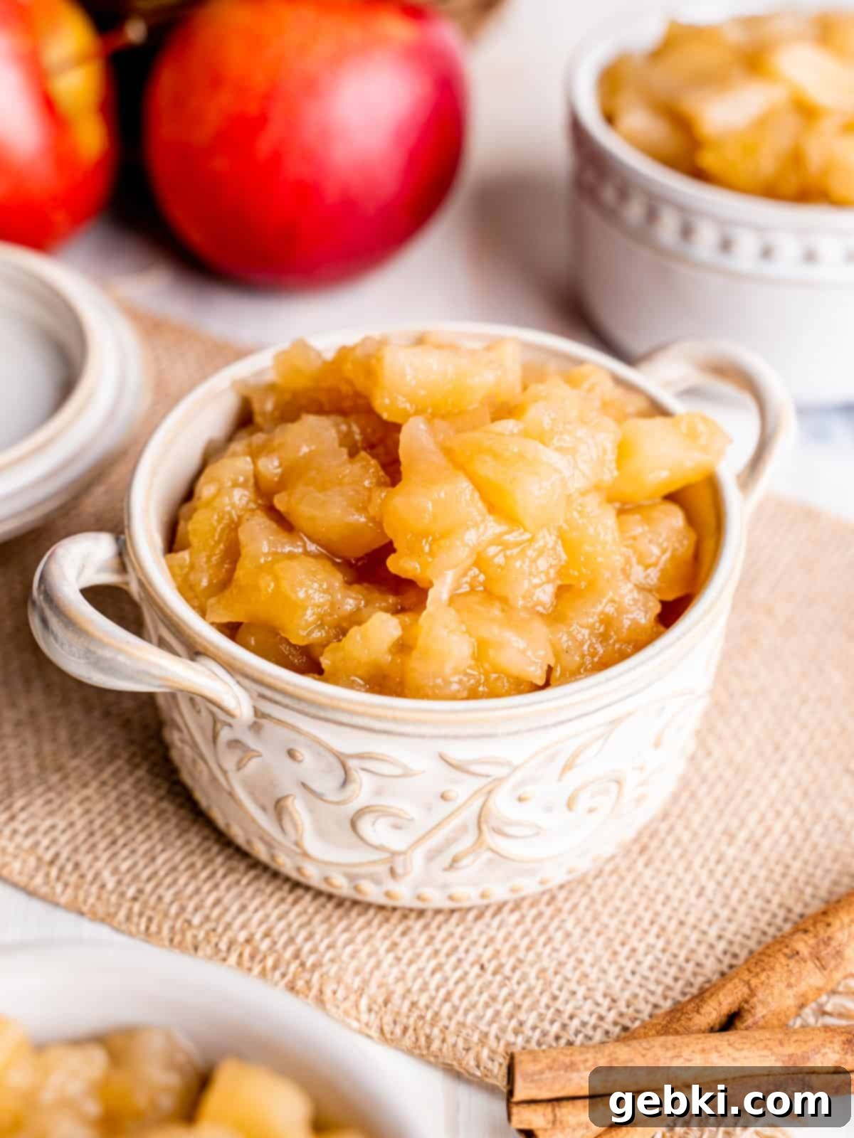 Rustic Apple Chunks 5 A small white ramekin filled with homemade chunky applesauce, garnished with a sprig of mint, ready to be enjoyed as a refreshing snack or dessert.