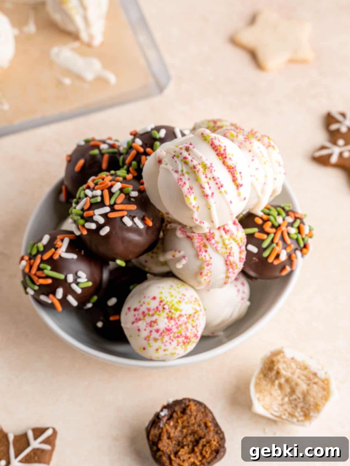 No-Bake Christmas Cookie Truffles 2 A bowl filled with various Christmas cookie truffles, featuring both sugar and gingerbread flavors, generously decorated with festive sprinkles. They are perfect for holiday gifting or serving at parties.