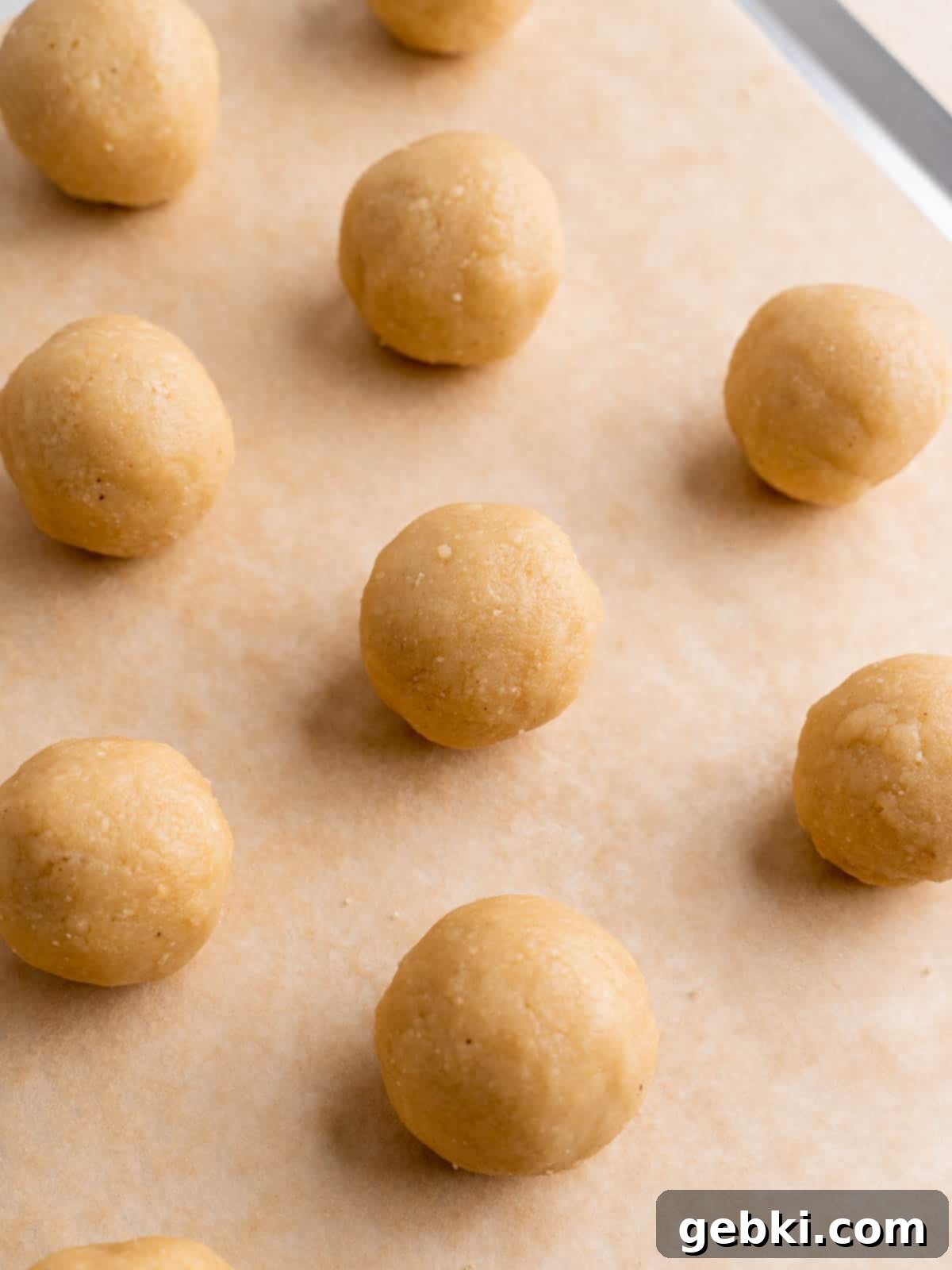 No-Bake Christmas Cookie Truffles 7 Perfectly rolled sugar cookie truffle balls arranged neatly on a baking sheet lined with parchment paper, ready for chilling.