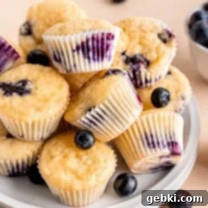 Bite-Sized Blueberry Bliss 10 A stack of perfectly golden mini blueberry muffins on a plate.