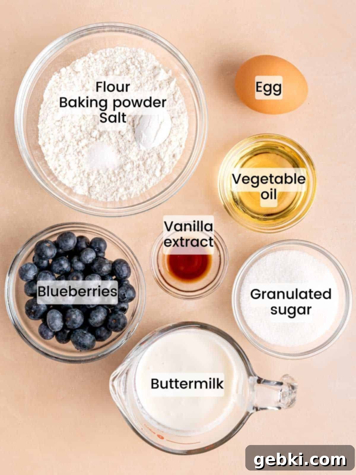 Bite-Sized Blueberry Bliss 3 Assortment of ingredients laid out, including flour, sugar, blueberries, buttermilk, oil, and vanilla extract, ready for making mini blueberry muffins.