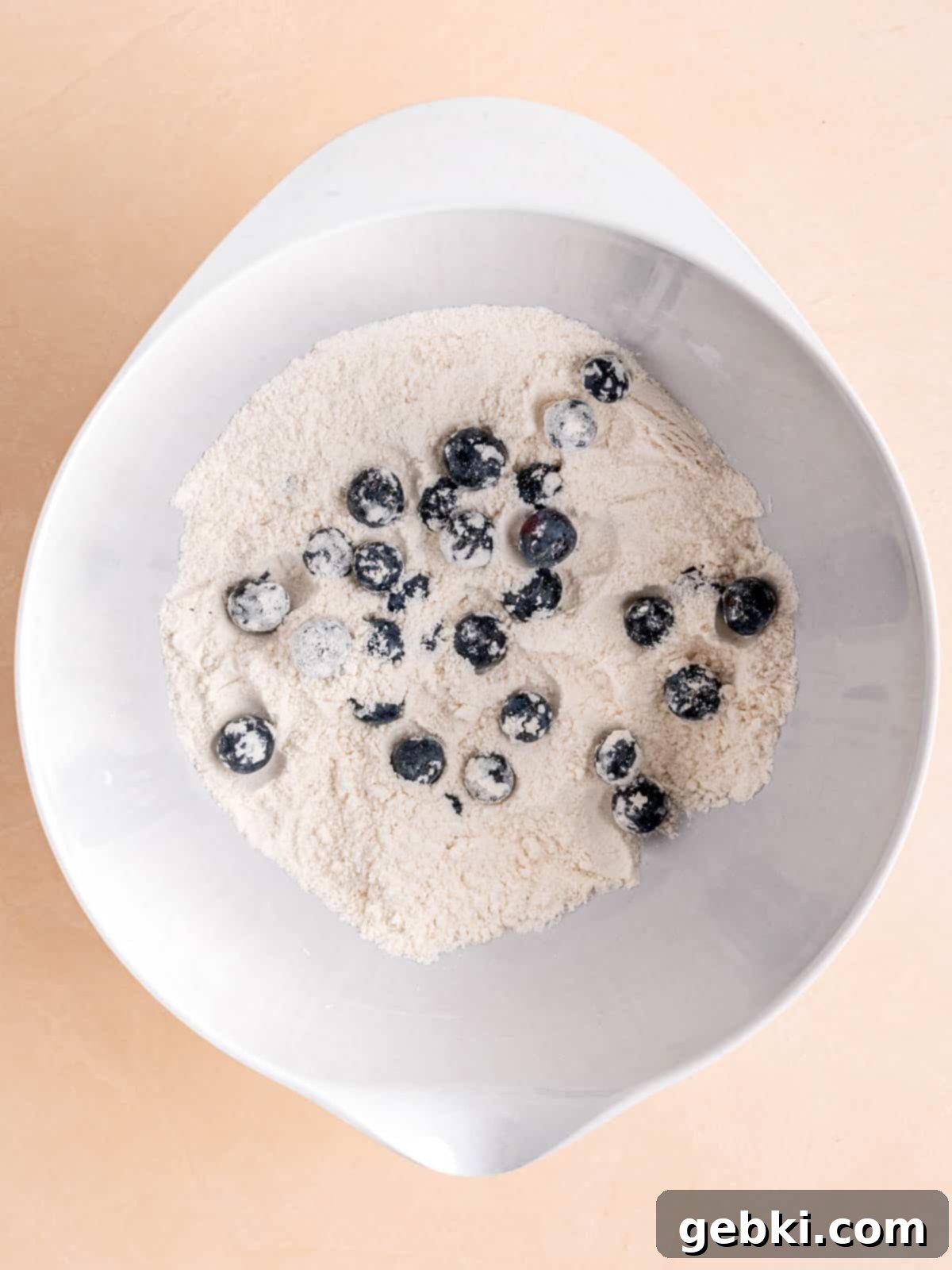 Bite-Sized Blueberry Bliss 4 Blueberries lightly coated in a flour mixture in a mixing bowl.
