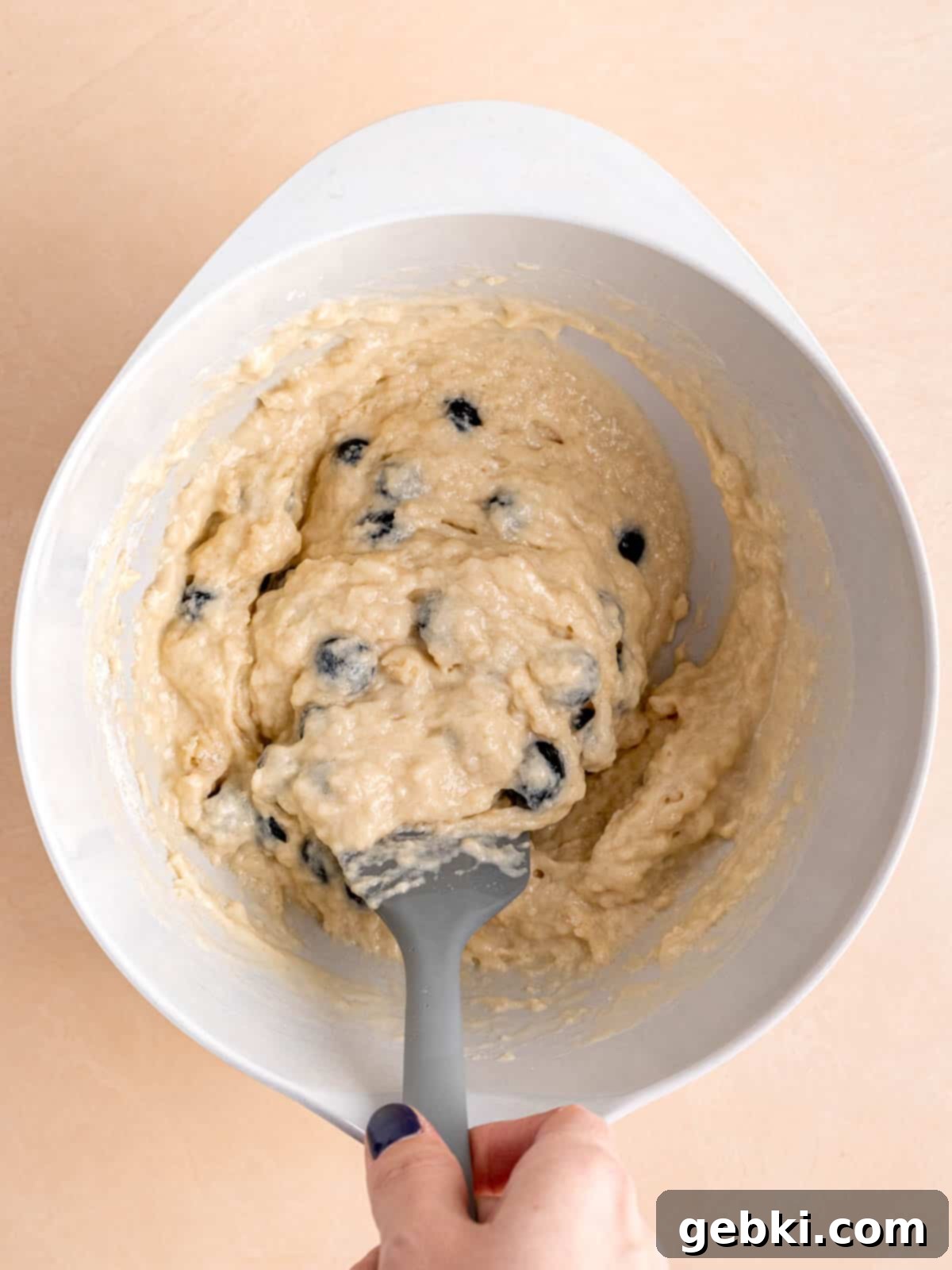 Bite-Sized Blueberry Bliss 6 Blueberry muffin batter in a bowl with a spatula, showing the gentle folding technique.