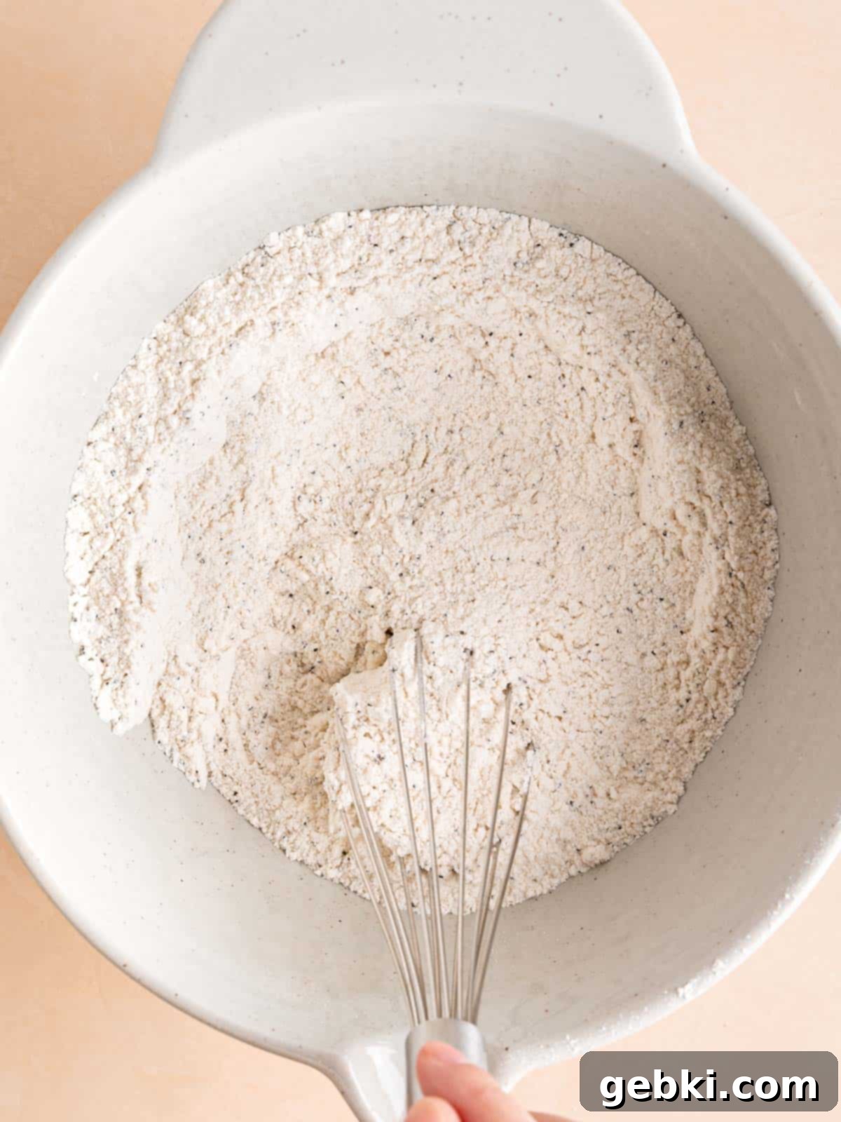Zesty Orange Poppy Seed Muffins with Glaze 4 Whisking together dry ingredients: flour, sugar, salt, baking powder, baking soda, and poppy seeds in a large mixing bowl.