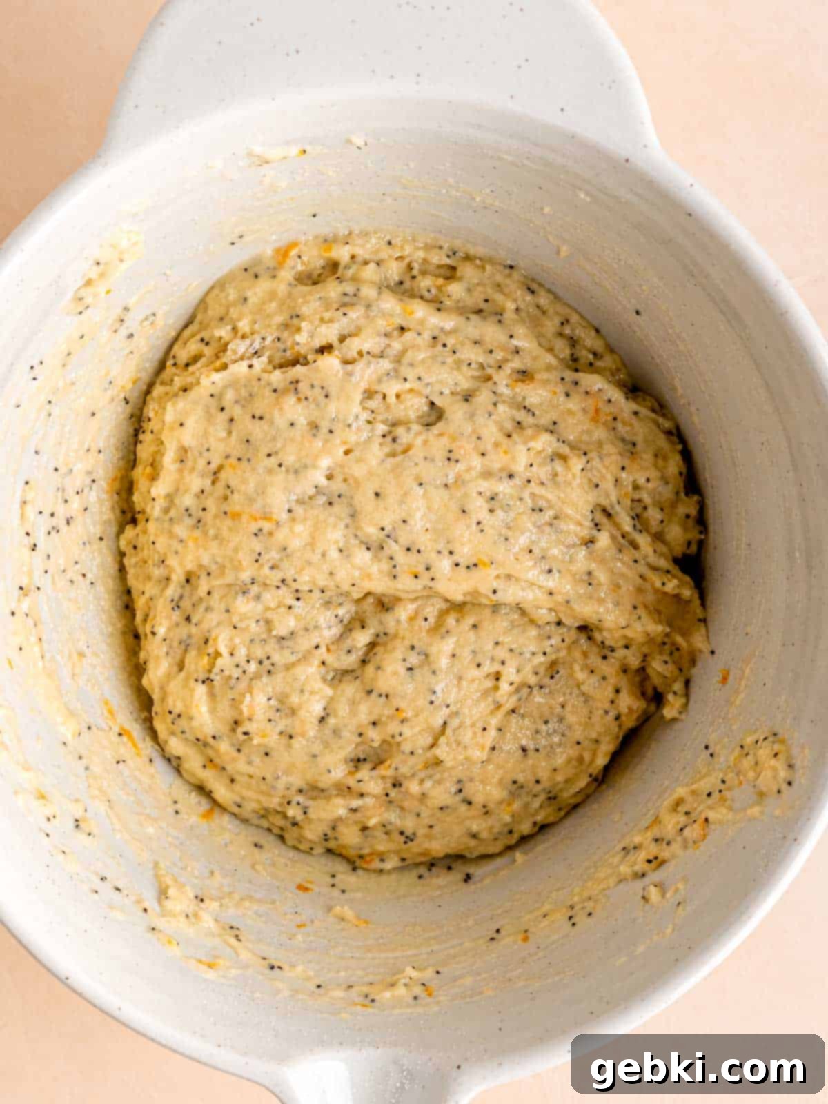 Zesty Orange Poppy Seed Muffins with Glaze 6 Muffin batter with orange zest and poppy seeds in a mixing bowl, lightly mixed.