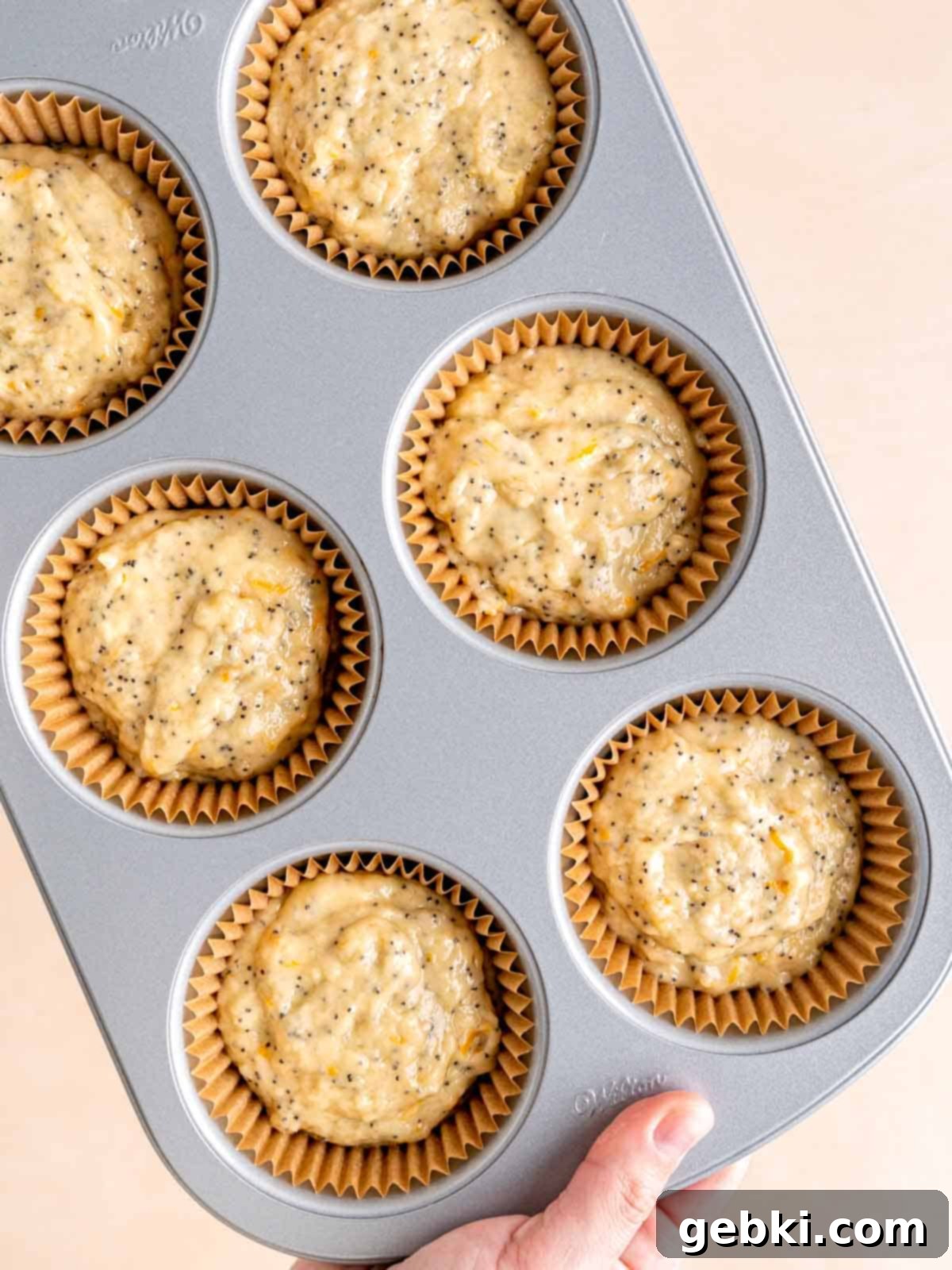 Zesty Orange Poppy Seed Muffins with Glaze 7 A jumbo muffin pan with liners filled with orange poppy seed muffin batter, ready for baking.
