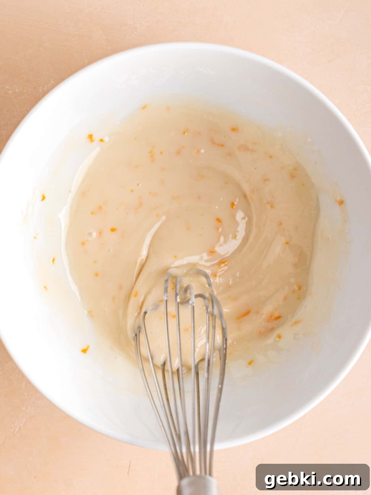Zesty Orange Poppy Seed Muffins with Glaze 8 Whisking together powdered sugar, milk, vanilla extract, and orange zest to make the glaze.