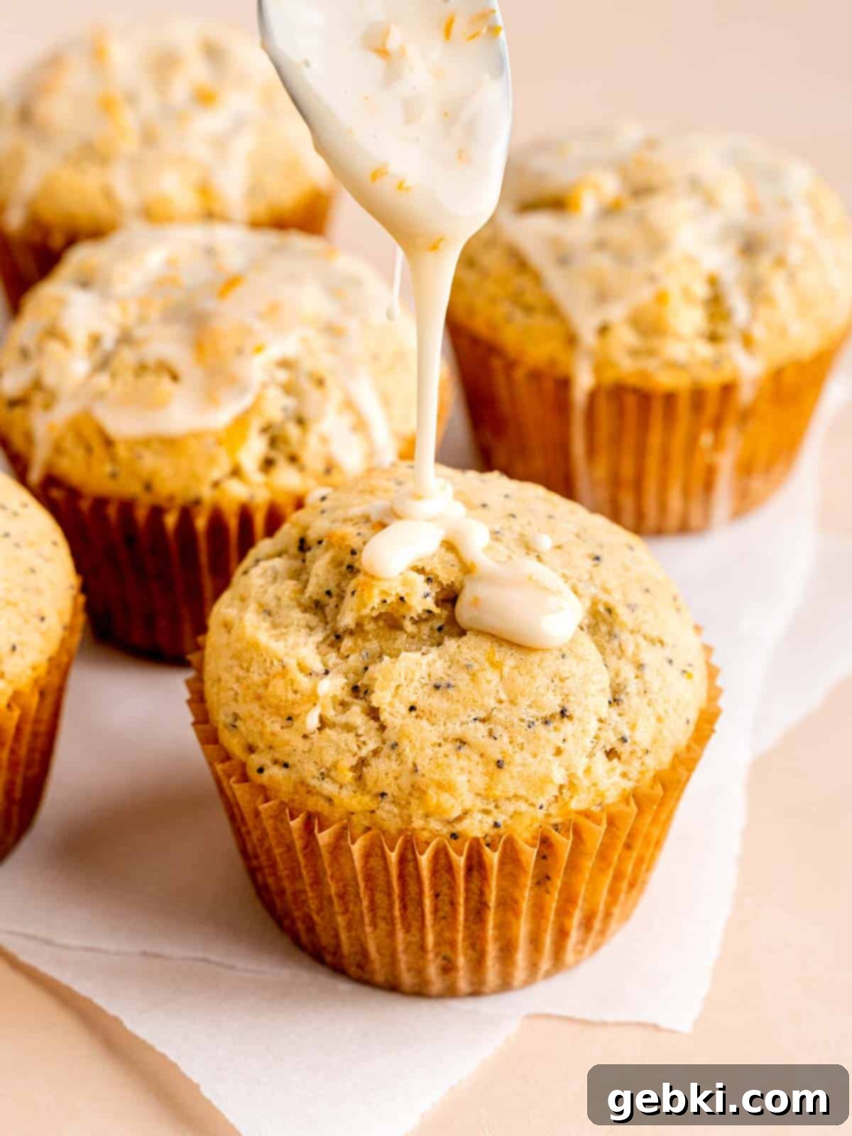 Zesty Orange Poppy Seed Muffins with Glaze 9 Drizzling vanilla orange icing generously over a cooled orange poppy seed muffin.