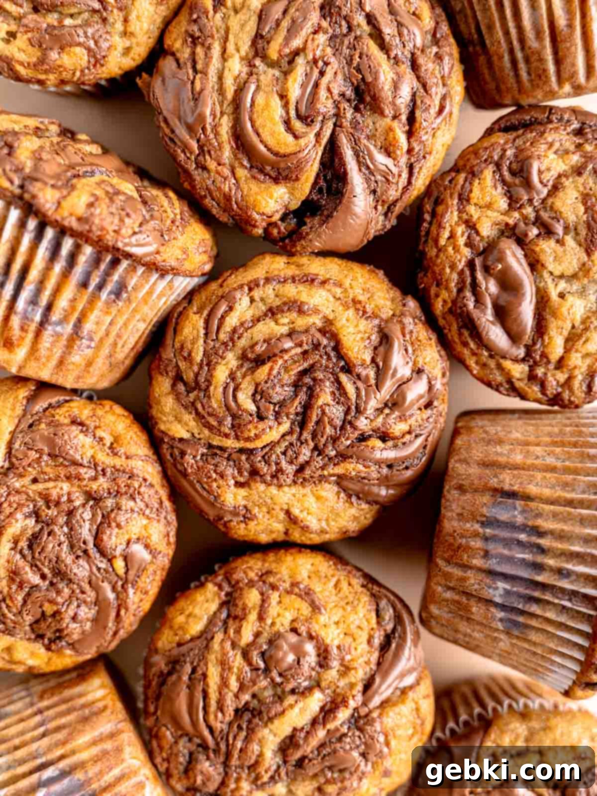 Marbleized Banana Nutella Muffins 2 Deliciously moist banana muffins with rich Nutella swirled on top and throughout the middle, showcasing their golden-brown tops and enticing chocolate patterns. A perfect visual for a sweet breakfast or snack.