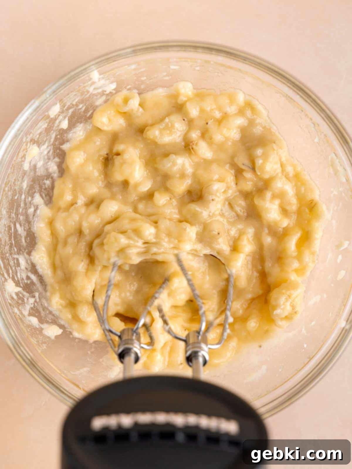 Marbleized Banana Nutella Muffins 4 Mashing perfectly overripe bananas in a bowl with a convenient Kitchenaid cordless hand mixer, showing the smooth consistency being achieved.