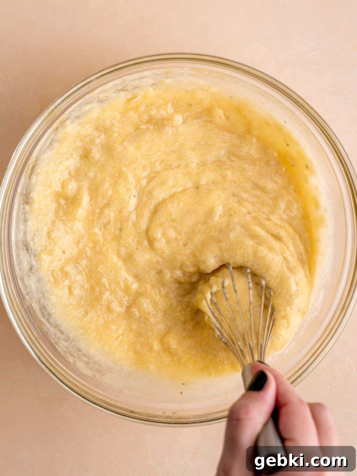 Marbleized Banana Nutella Muffins 5 Whisking together the luscious wet ingredients: melted butter, granulated sugar, a cracked egg, aromatic vanilla extract, creamy sour cream, and the prepared mashed bananas in a spacious mixing bowl.