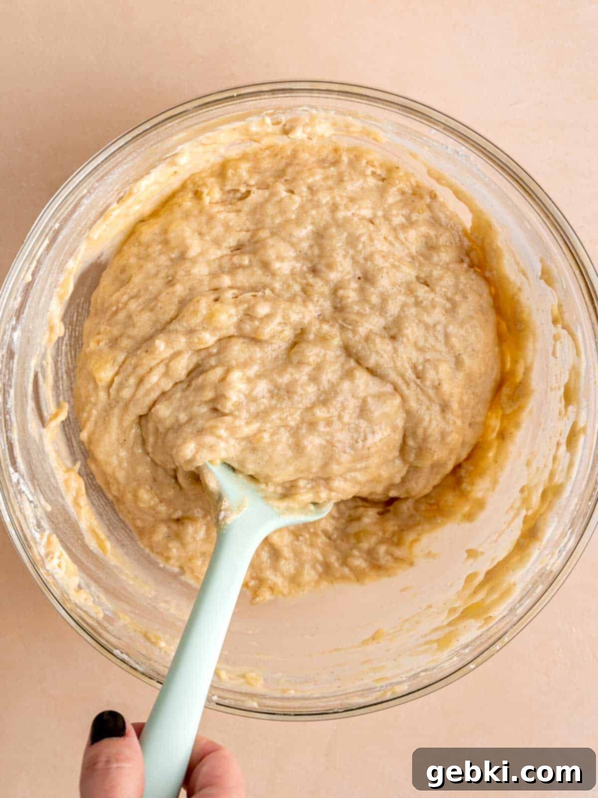 Marbleized Banana Nutella Muffins 7 A bowl filled with moist, perfectly mixed banana muffin batter, with a rubber spatula resting gently inside, ready for the next step.