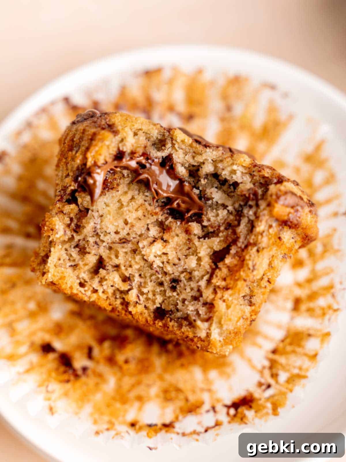 Marbleized Banana Nutella Muffins 10 A perfectly baked, moist banana and Nutella muffin with a visible bite taken out, clearly showcasing the delicious swirls of chocolate hazelnut spread throughout the fluffy interior. Ready to be savored.