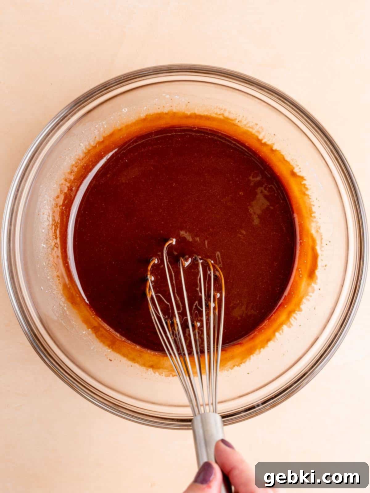 Melted unsalted butter and chocolate chips being whisked together for rich brownie batter.