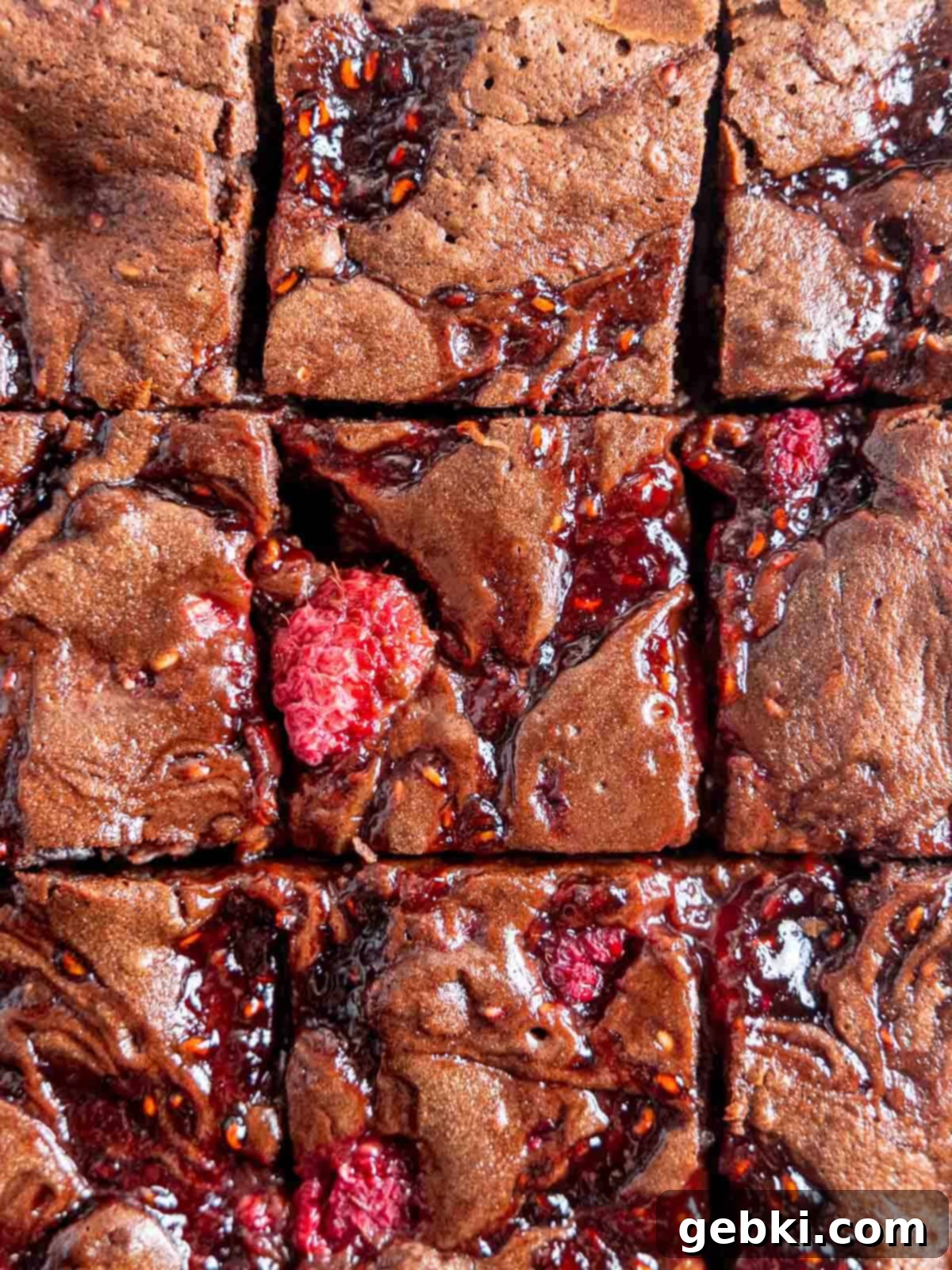 Decadent Raspberry Chocolate Fudge Brownies 2 Top view of fudgy chocolate raspberry brownies cut into perfect squares, showcasing the vibrant red raspberries and rich chocolate texture.