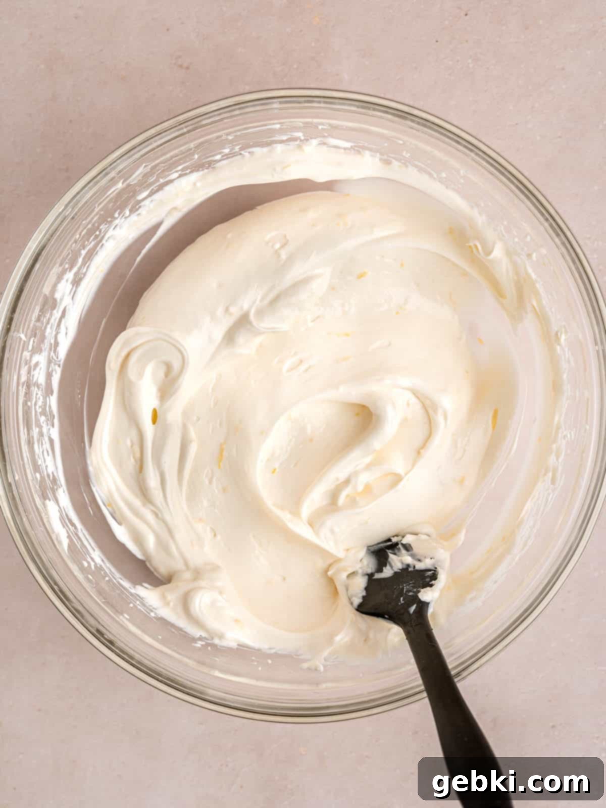 Cream cheese, sugar, sour cream, lemon juice, lemon zest, and vanilla extract mixed together in a bowl.