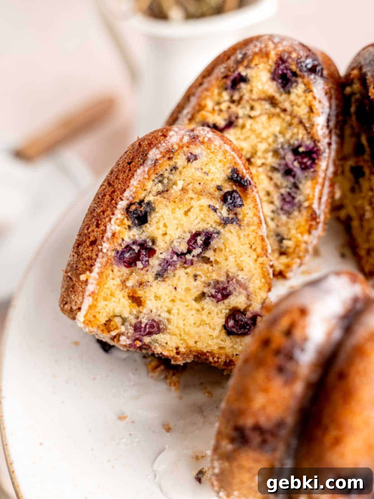 Irresistible Blueberry Sour Cream Coffee Cake 2 A slice of blueberry sour cream coffee cake sticking out of a bundt cake.