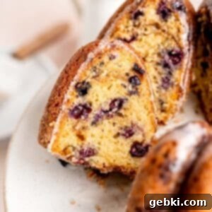 Irresistible Blueberry Sour Cream Coffee Cake 11 A slice of blueberry sour cream coffee cake sticking out of a bundt cake.