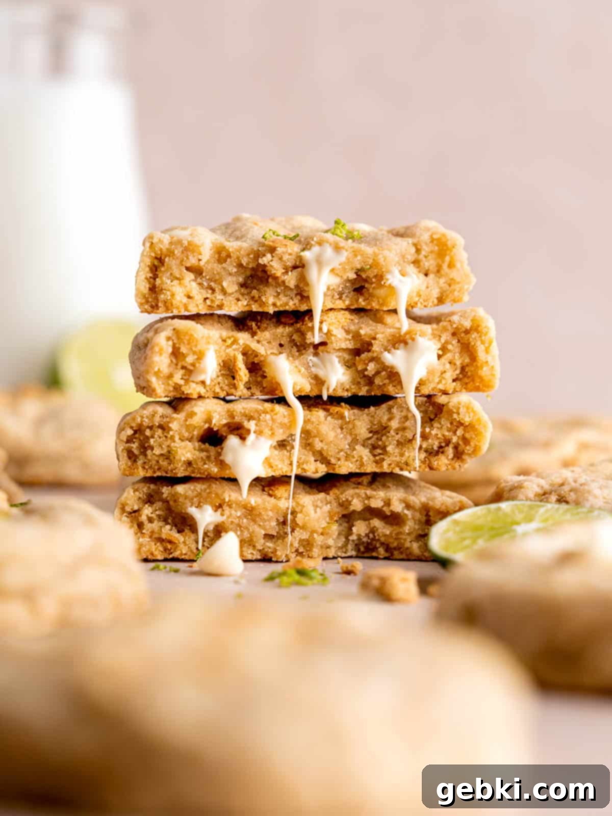 Zesty Key Lime White Chocolate Chip Cookies 2 A stack of white chocolate chip key lime cookies, garnished with extra white chocolate chips and graham cracker crumbs, showcasing their vibrant green hue and chewy texture.