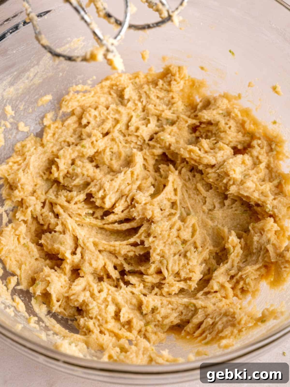 Zesty Key Lime White Chocolate Chip Cookies 4 Butter, granulated sugar, light brown sugar, key lime zest, egg, and vanilla extract are being creamed together in a mixing bowl with an electric mixer.