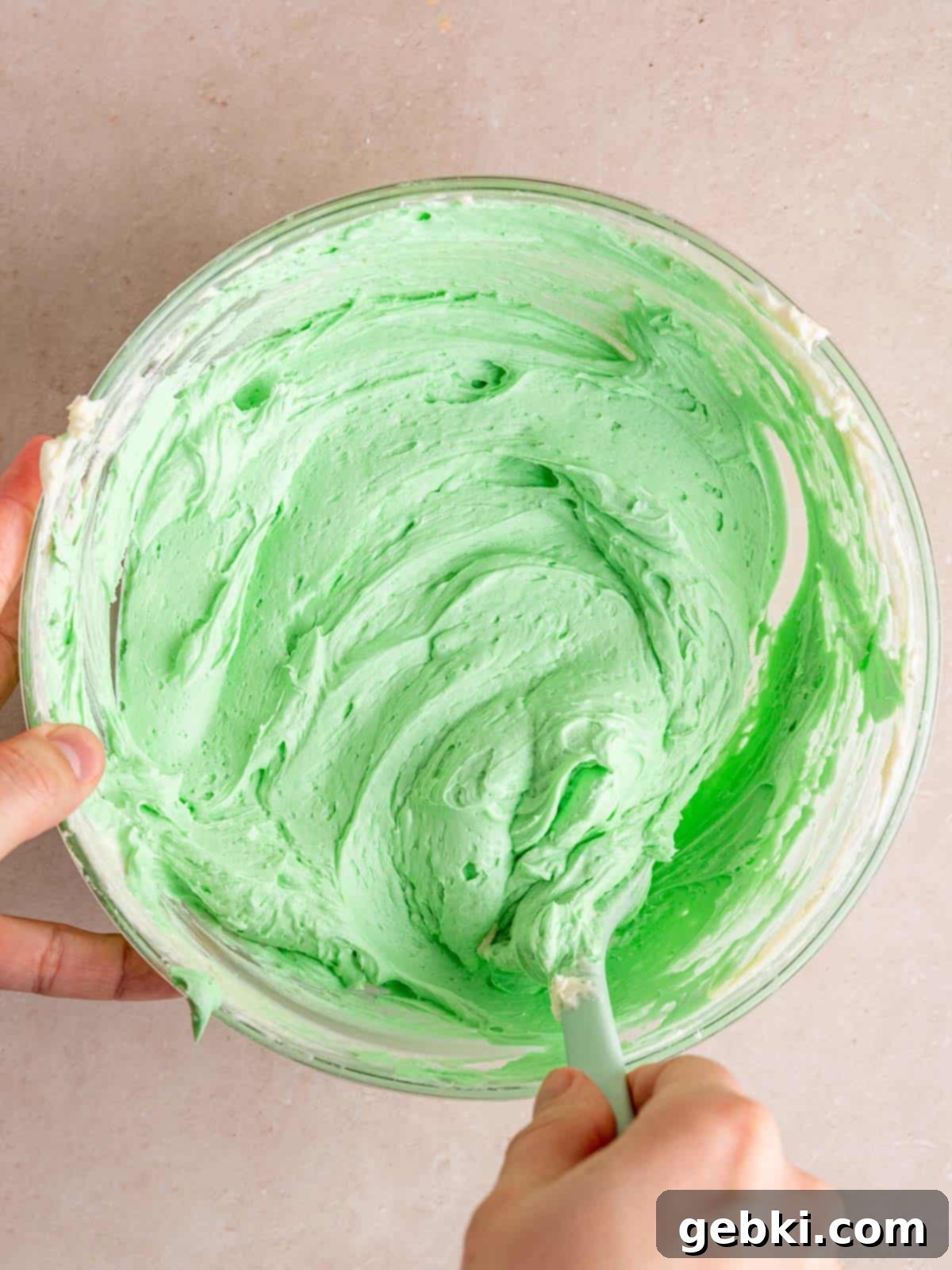 Minty Chocolate Indulgence 8 Mixing green mint buttercream in a bowl, showing its vibrant color and smooth texture.