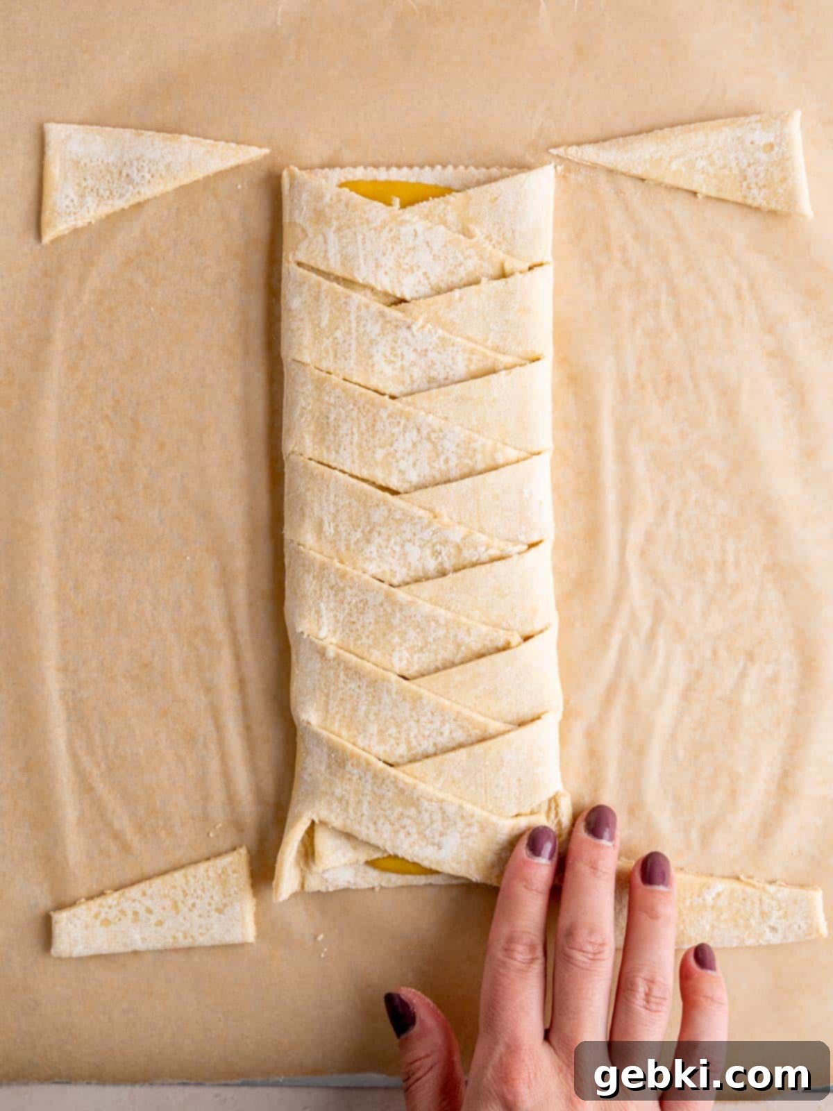 Diagonal strips of puff pastry are alternately folded over a central almond filling, forming an elegant lattice pattern.