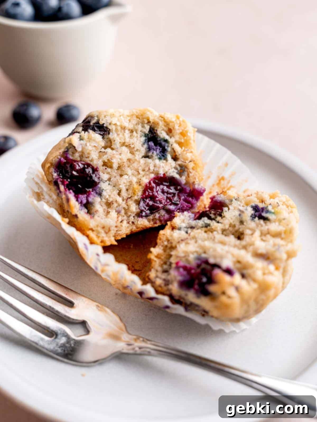 Irresistible Blueberry Banana Muffins 8 A banana blueberry muffin cut in half on a plate.