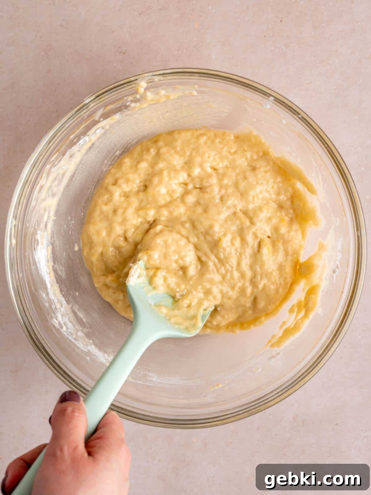 Lemon donut batter in a bowl with a spatula, showing the folded consistency.