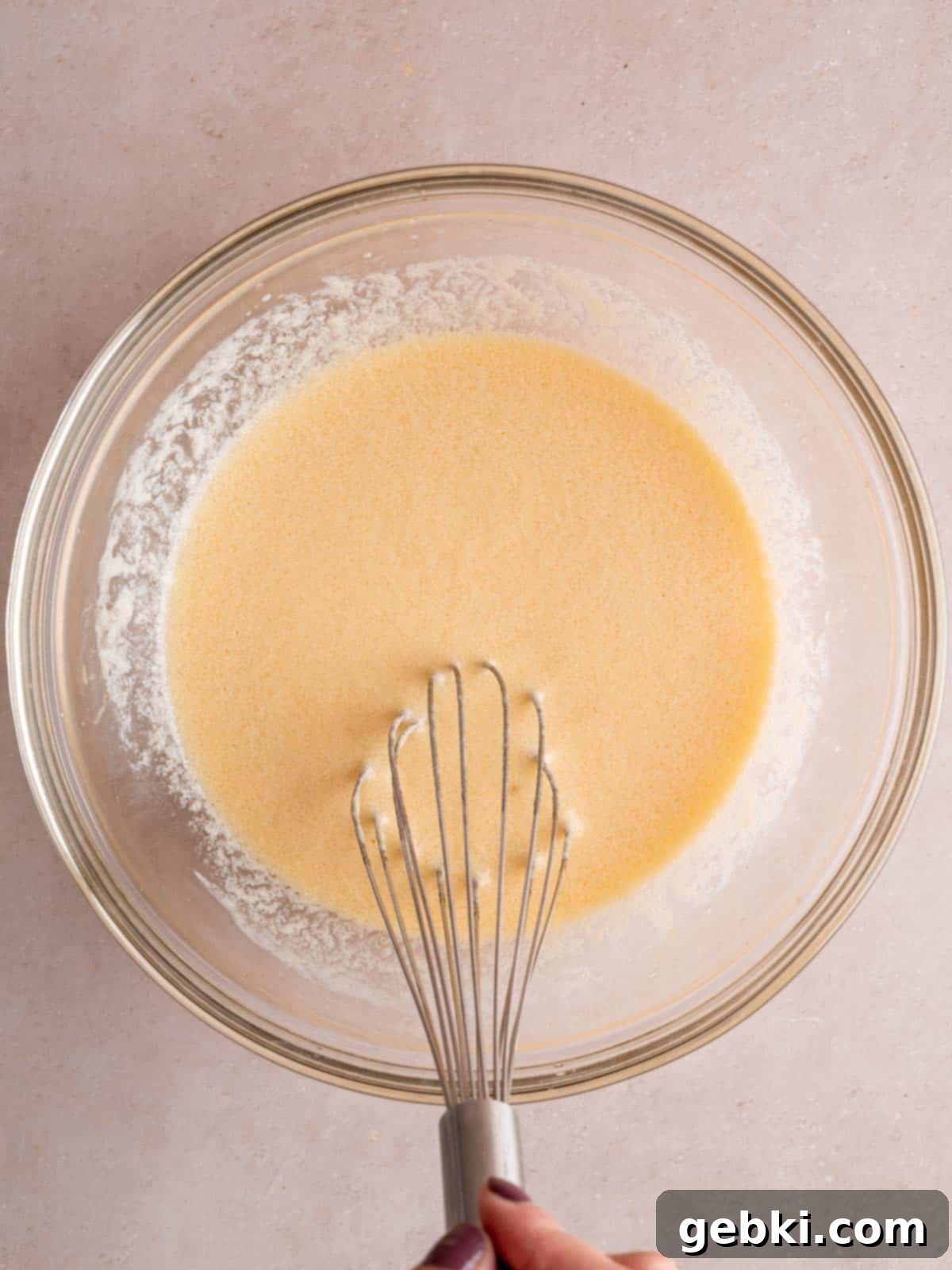 Whisking eggs, vegetable oil, cherry kefir, and vanilla extract together in a bowl to create the wet ingredients.