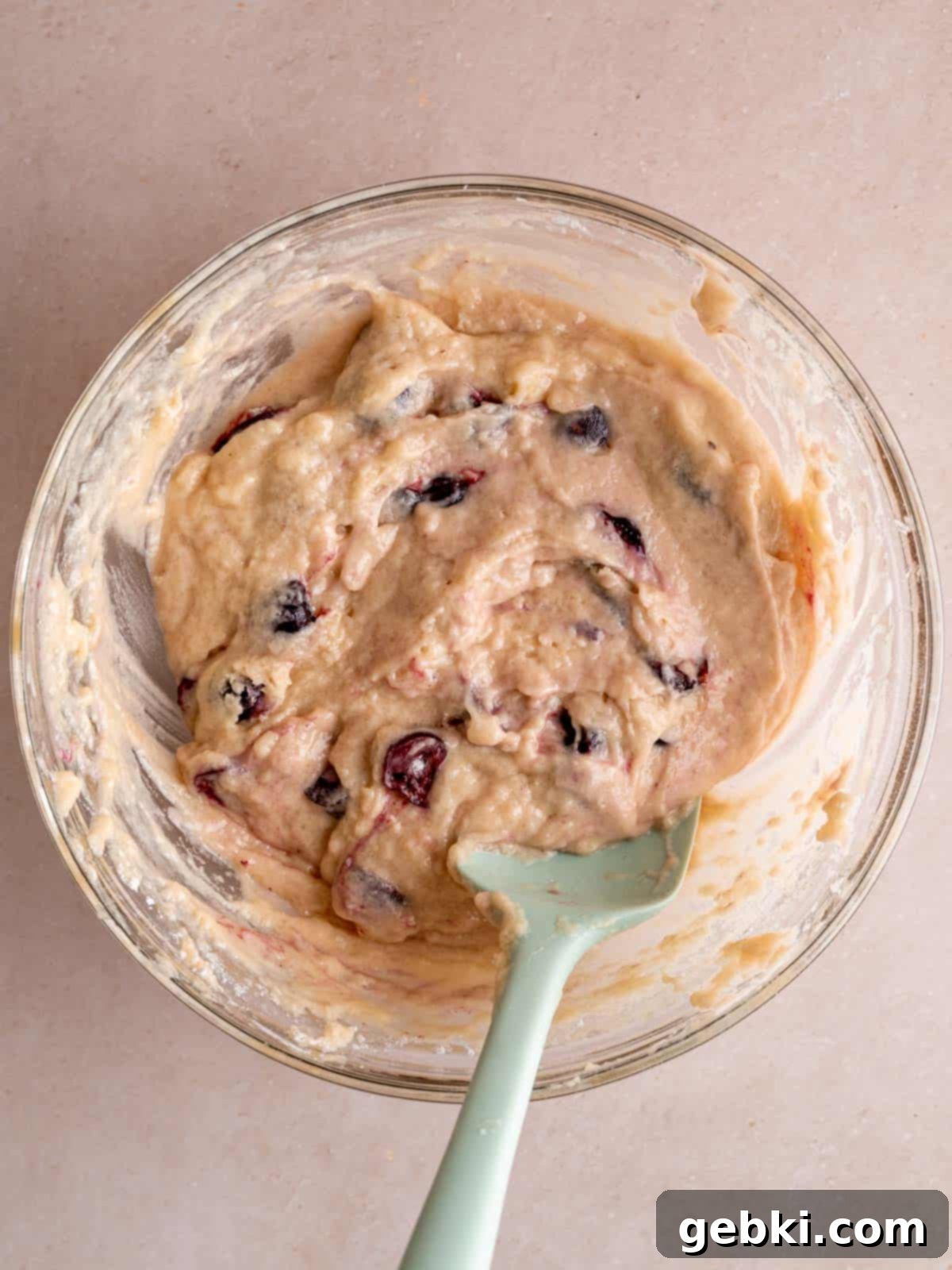 Cherry cake batter in a bowl with a spatula, showing the perfect consistency.