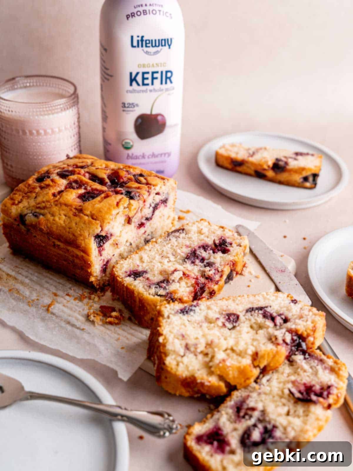 A cherry cake cut into slices next to a bottle of Lifeway Black Cherry Kefir, highlighting the key ingredient.