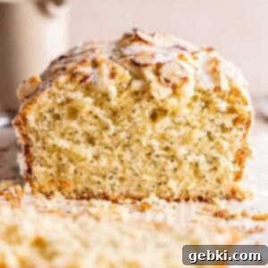 A perfectly baked loaf of almond poppy seed cake, glazed and topped with toasted almonds.