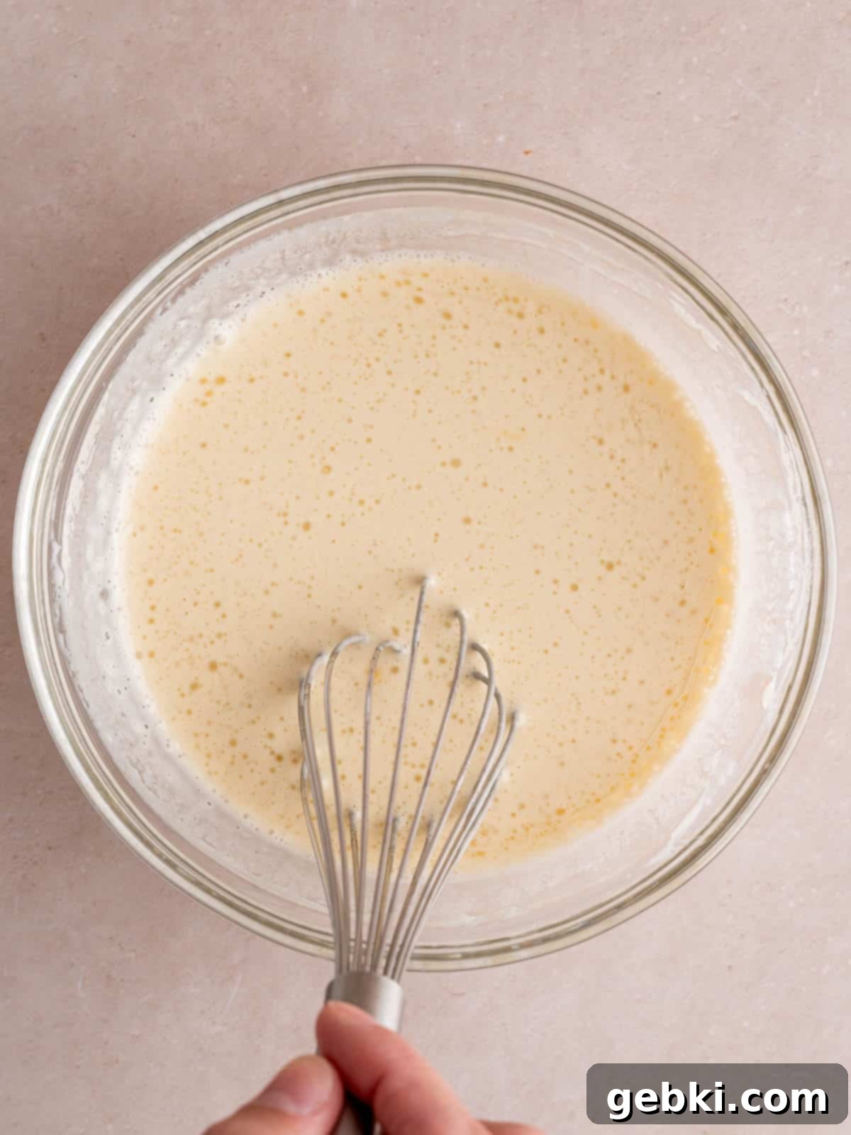 Turn Sourdough Discard Into Fluffy Pancakes 5 A separate mixing bowl showcasing the wet ingredients: a cracked egg, a pour of vegetable oil, a generous scoop of sourdough discard, and milk, being smoothly combined with a whisk.