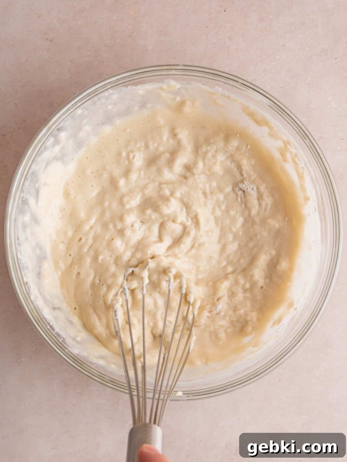 Turn Sourdough Discard Into Fluffy Pancakes 6 The combined sourdough discard pancake batter in a bowl with a whisk, showing a slightly lumpy but well-mixed consistency, indicating readiness for cooking.