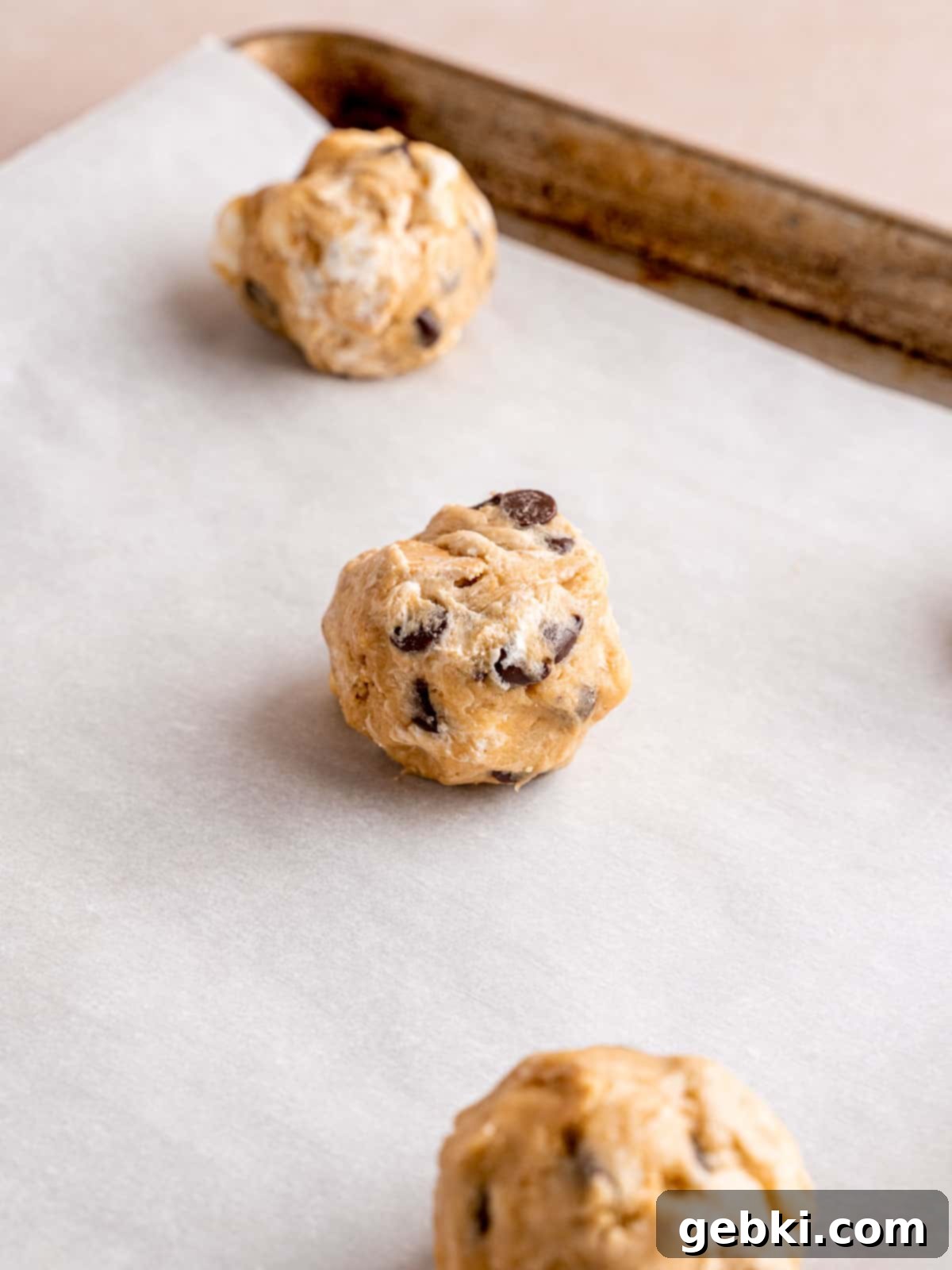 Cookie dough balls on a parchment paper lined baking sheet.