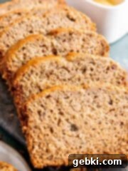 Slices of sourdough discard banana bread, some with added walnuts, beautifully arranged on a rustic cutting board.