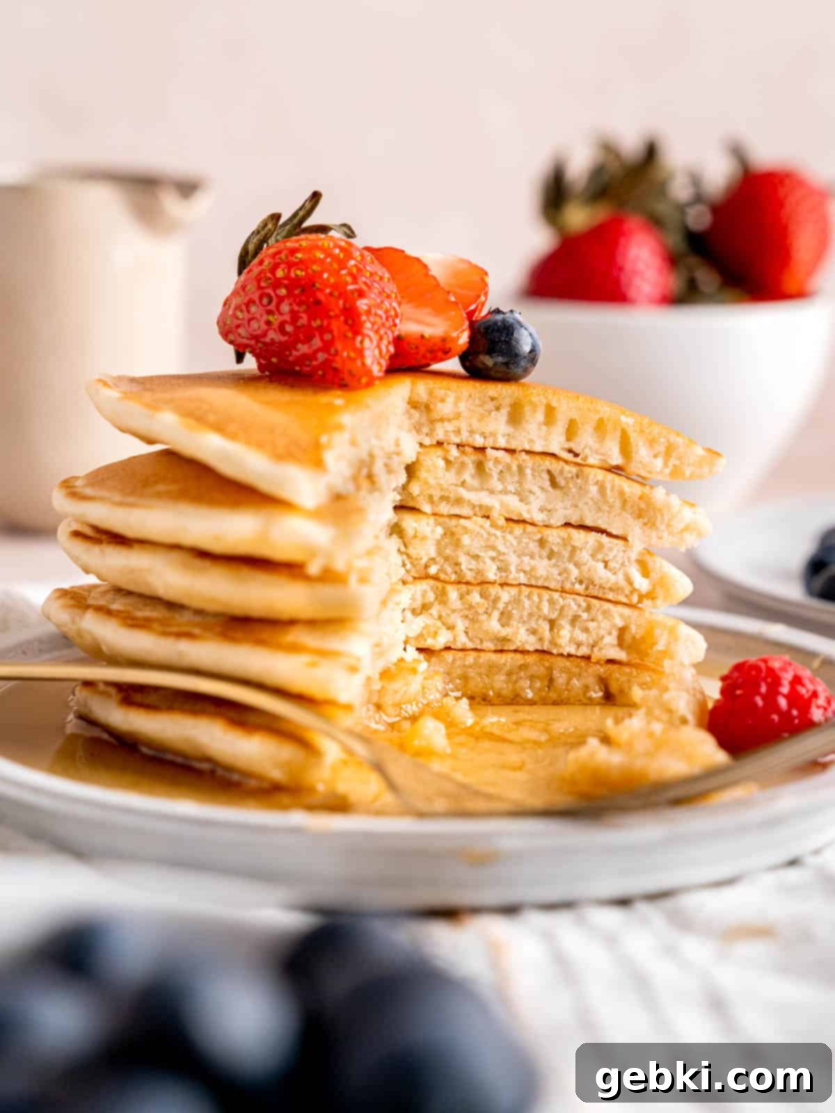 A delectable stack of golden brown sourdough pancakes with a piece cut out, revealing the soft, airy interior, ready for breakfast.