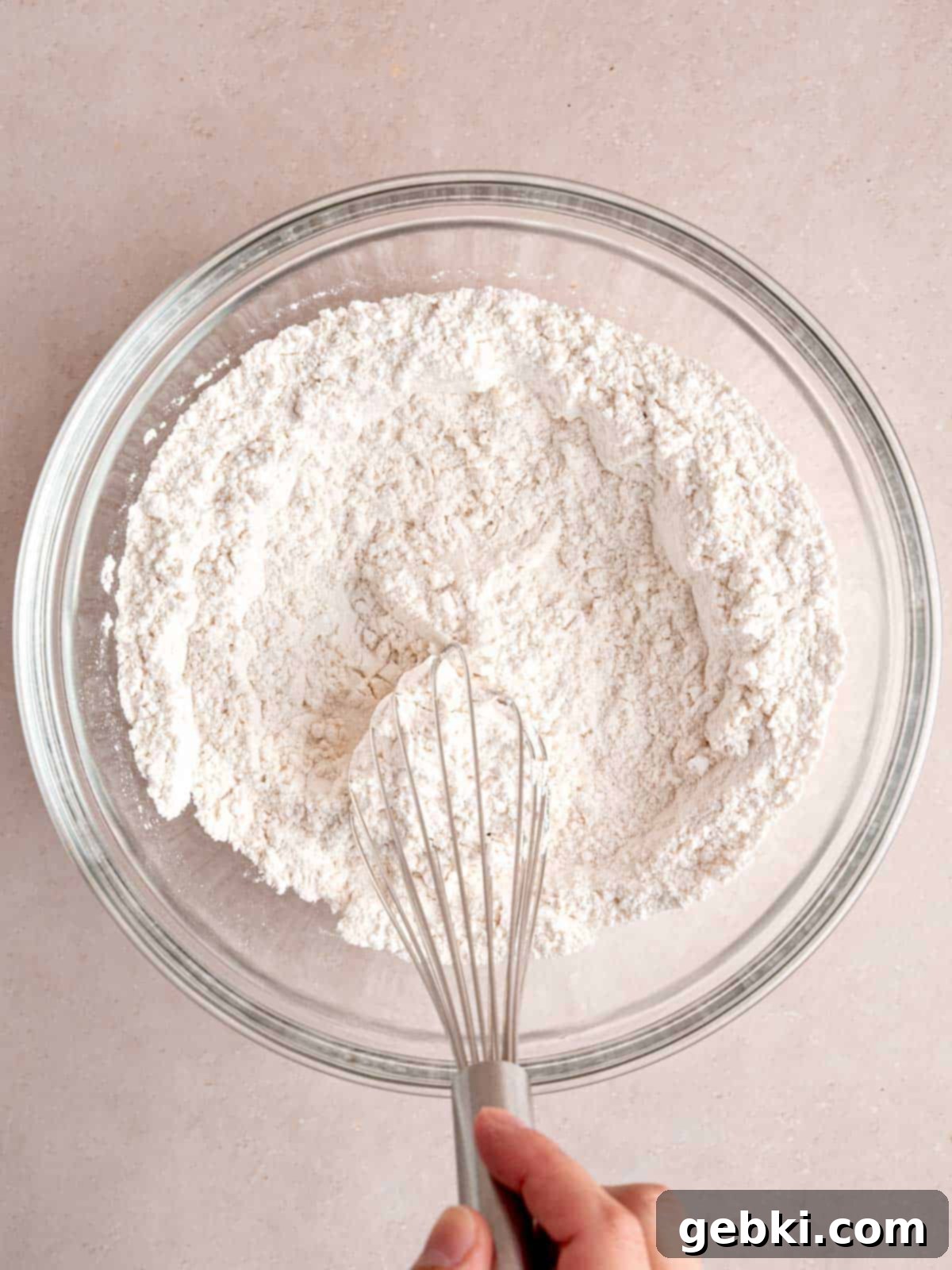 Whisking together dry ingredients: flour, baking powder, baking soda, and salt in a large mixing bowl.