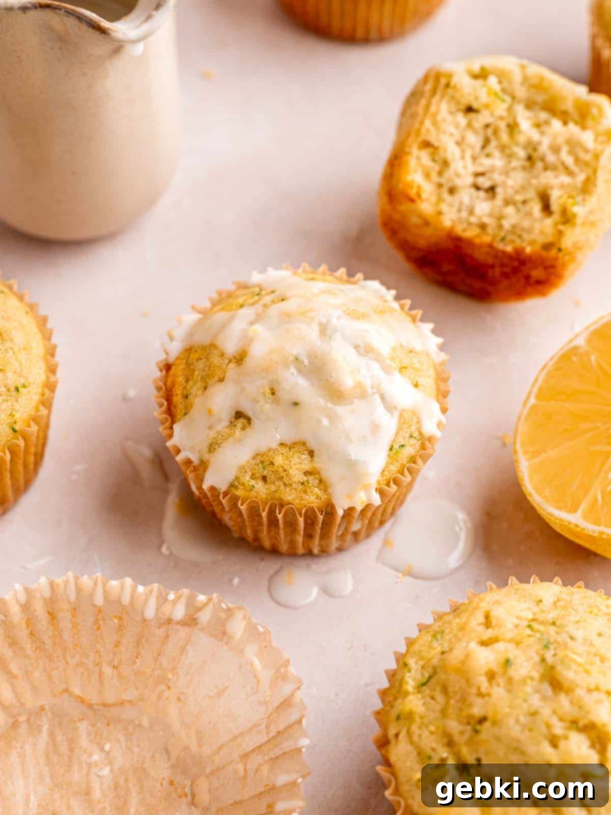 Moist lemon zucchini muffins with a glistening lemon glaze drizzled over them.