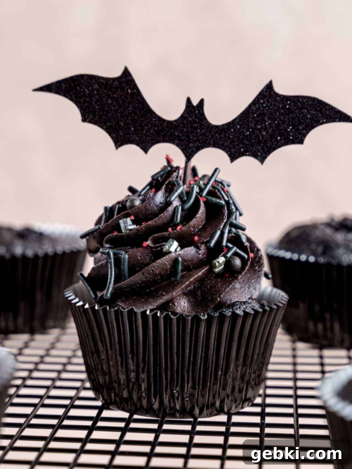 A black velvet cupcake with sprinkles and a bat cupcake topper.